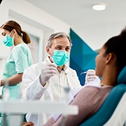 Smiling dentist talking to patient in treatment chair