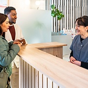 Couple smiling while talking to dental assistant in lobby